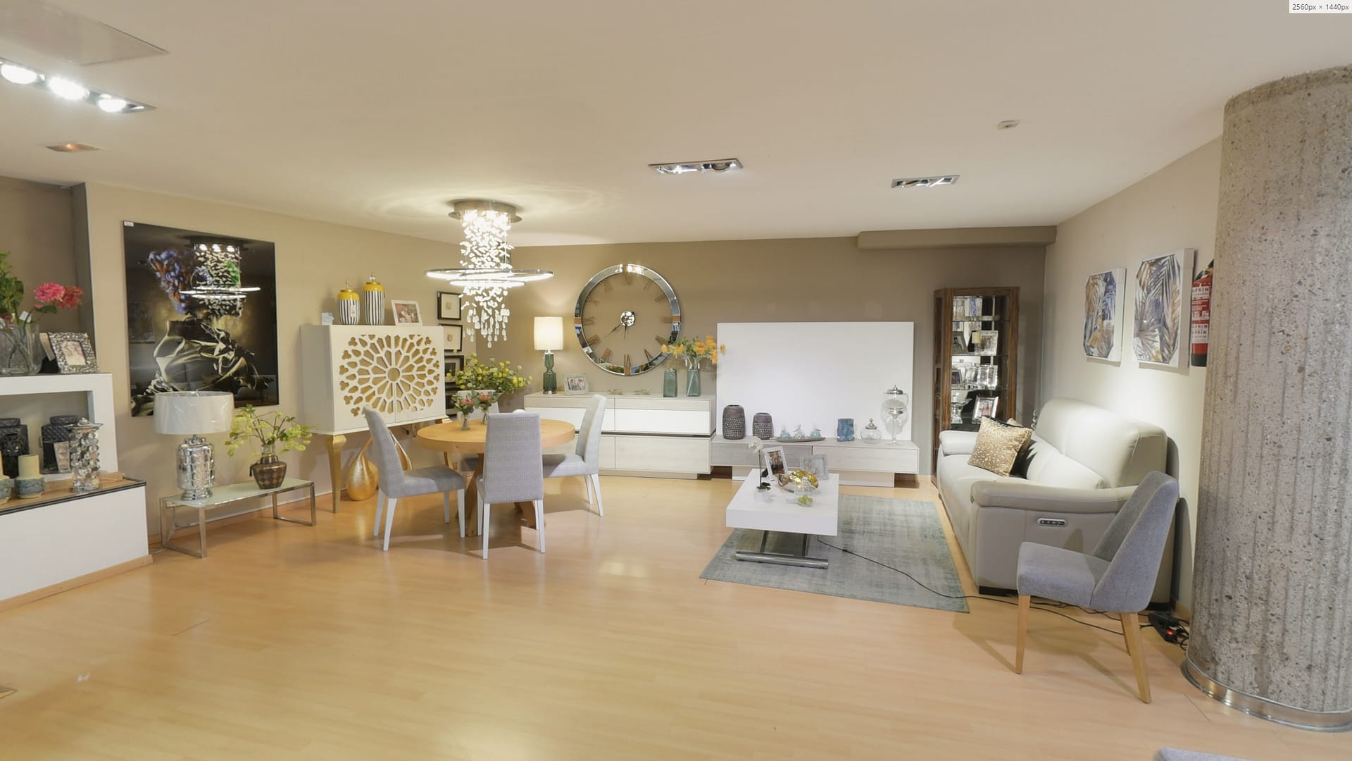Tienda de Muebles en Barcelona, mobiliario a medida y diseño - Temas Mobiliario Conjunto de salón con mueble de TV blanco, mesa de comedor redonda y aparador con detalles geométricos bajo una lámpara de araña moderna.